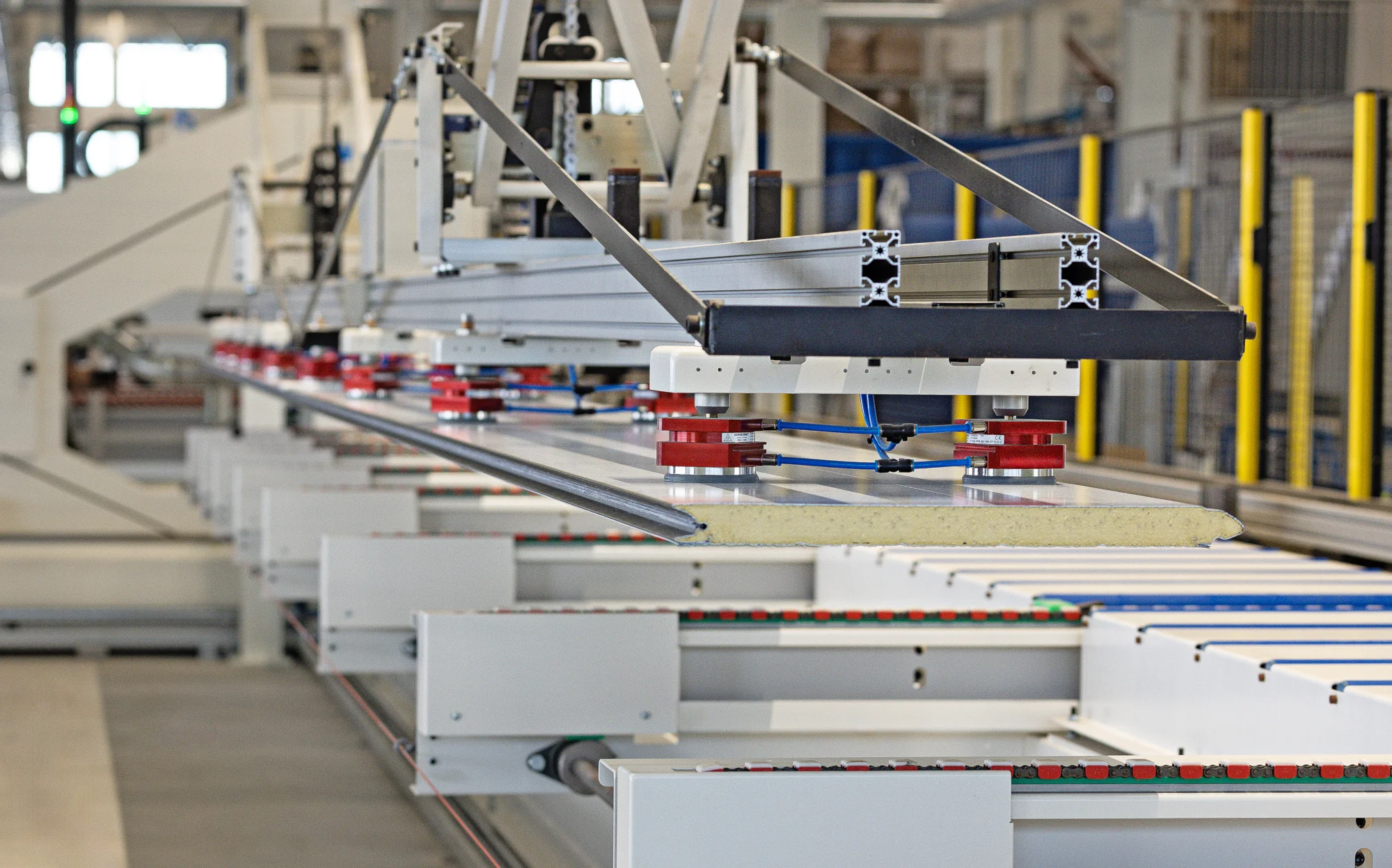 Maatwerk manipulator met magneet grijpers voor het automatisch aanvoeren van 13 meter sandwichpanelen in de productielijn voor garagedeuren.