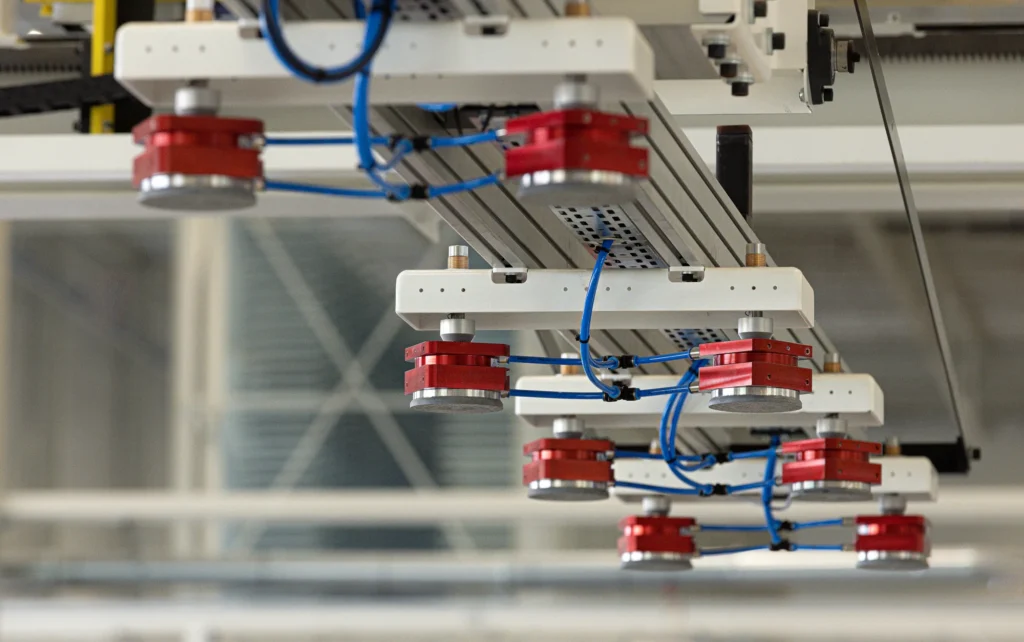 Maatwerk manipulator met magneet grijpers voor het automatisch aanvoeren van 13 meter sandwichpanelen in de productielijn voor garagedeuren.