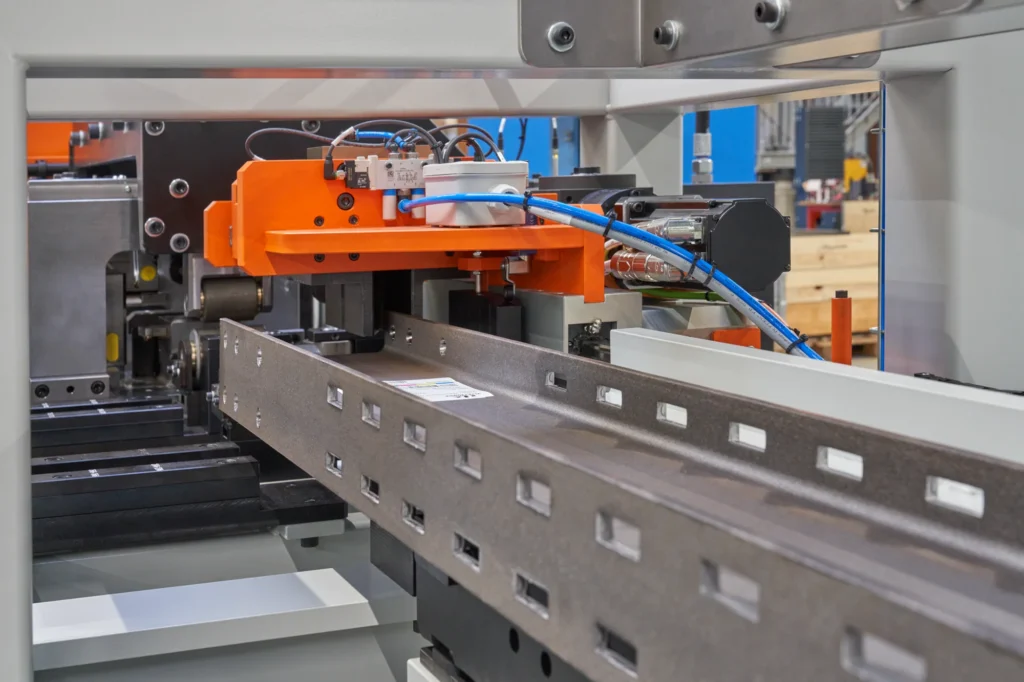 Detail van de uitvoerzijde waar de geponste patronen in de balken zichtbaar zijn. De balken zijn klaar voor verdere verwerking.