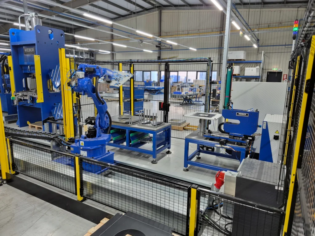 Een robot op track neemt automatisch verschillende lasergesneden platen uit een magazijn en positioneert deze op een draaitafel met automatische clinchunit. De platen worden vervolgens aan vier zijden aan elkaar geclinched. Na bewerking worden de samengestelde platen automatisch gepalletiseerd.